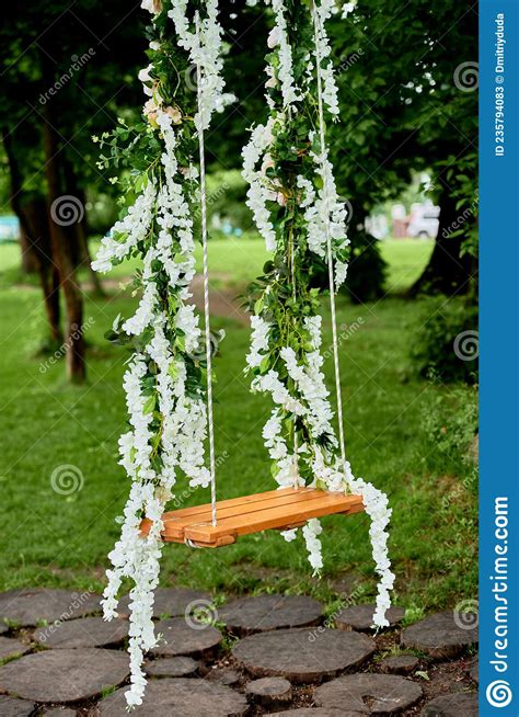 Wedding Swing Decorated With White Flowers Hanging On Tree In Garden