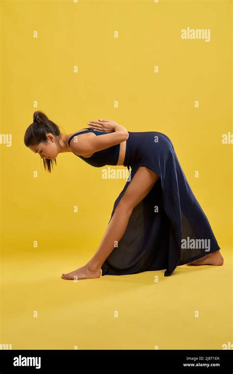 Slim Woman Bending Forward Keeping Hands Behind Back While Doing Yoga