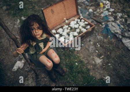 A Homeless Girl Is Sitting On A Garbage Dump Next To A Suitcase With
