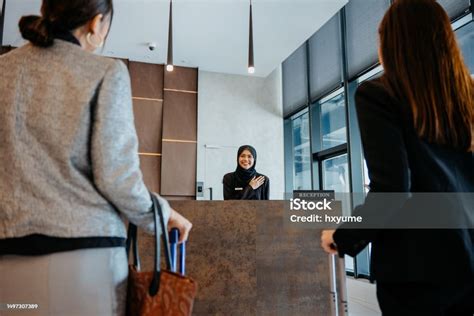 Hotel Receptionist Welcoming Guests At Reception Check In Counter Stock