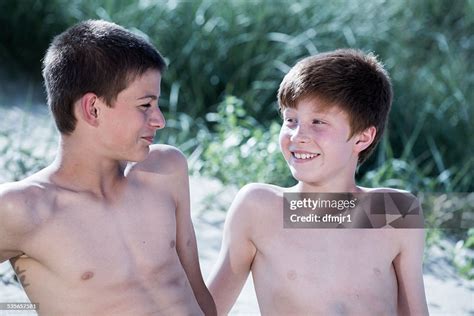 Two Boys Sitting On Beach Looking At Each Other Stock Photo Getty Images