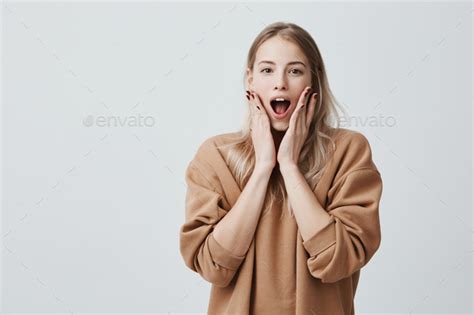 Indoor Shot Of Stupefied Stunned Blonde Woman Keeps Mouth Widely Opened