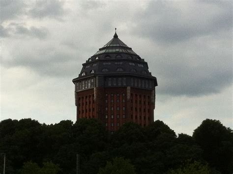 A Tall Building With A Dome On Top Surrounded By Trees And Clouds In