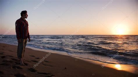 Man Standing On The Beach And Looking Into Sunset Stock Photo By