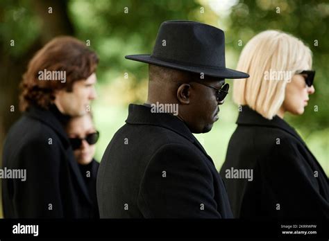 Side view of people wearing all black with sunglasses standing in