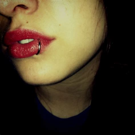 A Womans Face With Red Lipstick And Piercings On Her Nose In The Dark