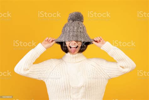 Playful Millennial Woman Pulling Down Woollen Hat And Sticking Out Her