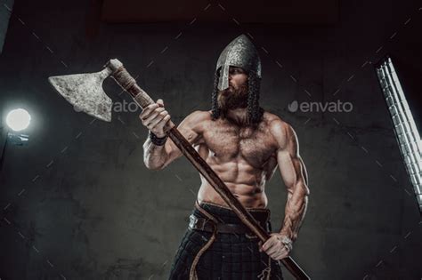 Viking With Naked Torso And Beard Posing In Dark Background Stock Photo