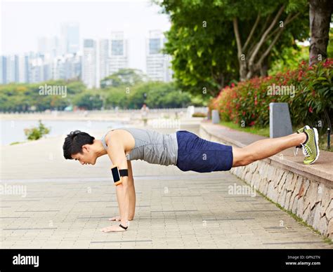 Asian Young Man Doing Exercising By Doing Push Ups In A City Park Stock