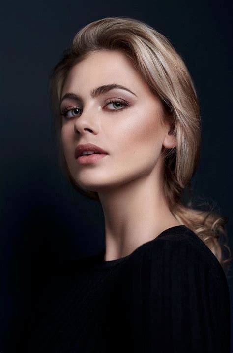 A Woman With Blonde Hair And Makeup Looks Into The Distance While