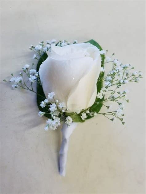 A Single White Rose Boutonniere With Babys Breath Greens And White