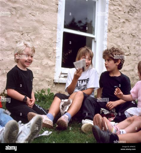 British Children Sitting Outside In The Garden In Playing A Pass The