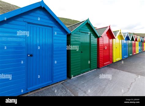 Row Of Brightly Coloured Wooden Beach Huts Along The West Cliff