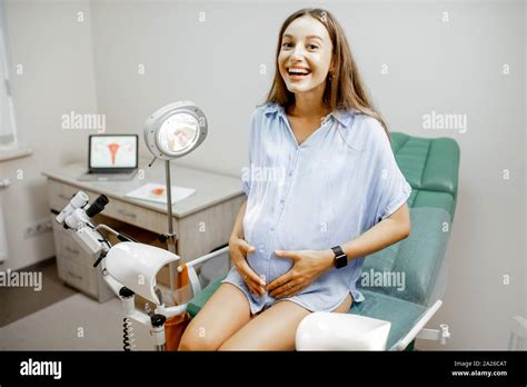 smiling pregnant woman sitting on the gynecological chair before a medical examination by a