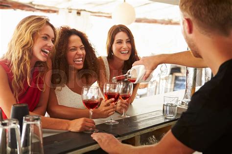 Three Female Friends Enjoying Drink At Outdoor Bar Stock Image Colourbox