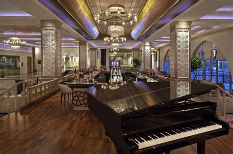 a grand piano in the middle of a large room with chandeliers and seating