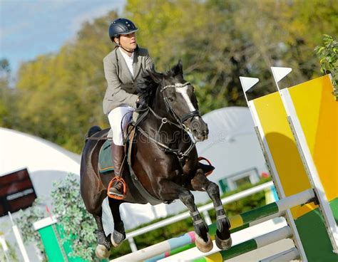 Black Horse And Girl In Uniform At Show Jumping Competition Stock