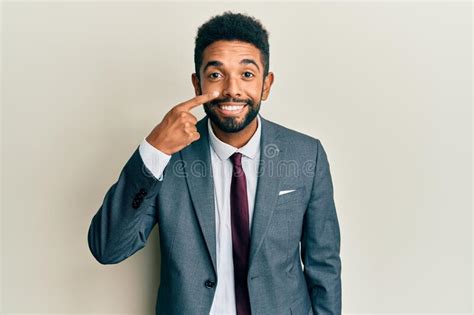 Handsome Hispanic Man With Beard Wearing Business Suit And Tie Pointing With Hand Finger To Face