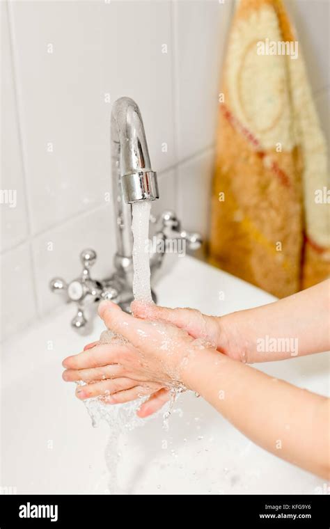 Little Girl Washing Her Hands In Bathroom Shallow Focus Stock Photo