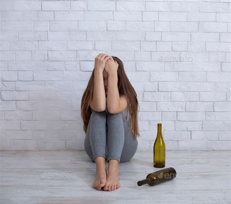 Alcoholism And Depression Concept Young Woman Crying On Floor At Home