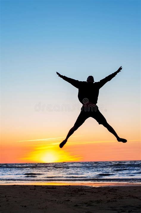 Jumping Man Silhouette On The Beach Multicolored Sunset Background
