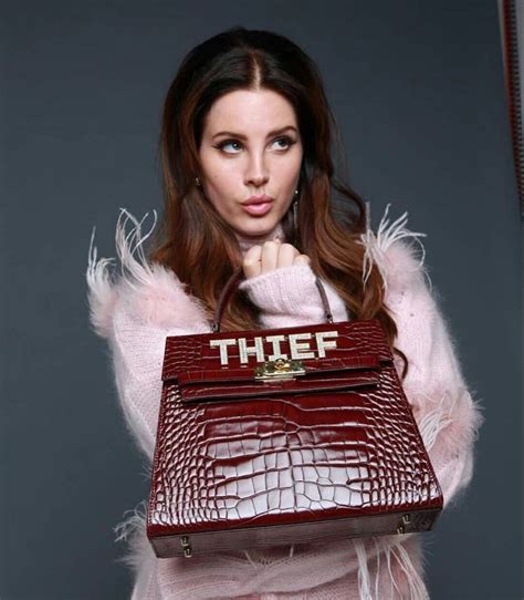 A Woman Holding A Purse With The Word Thief On It In Front Of Her Face