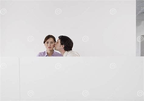 Man Kissing Female Colleagues Cheek In Office Cubicle Stock Image