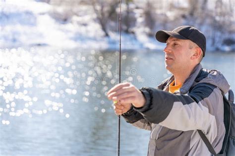 A Fisherman With A Fishing Rod Is Fishing On The River Bank Stock Photo
