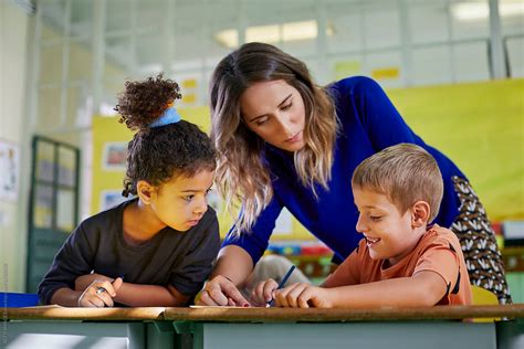 Teacher Helping Her Young Pupils In A Class Activity By Stocksy Contributor Alto Images