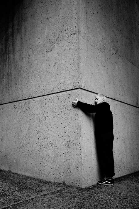 A Man Leaning Against A Wall With His Hand On The Side