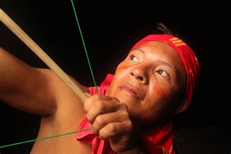 a hunter and dancer from kuna yala is looking up with his arch and arrow in the middle of the