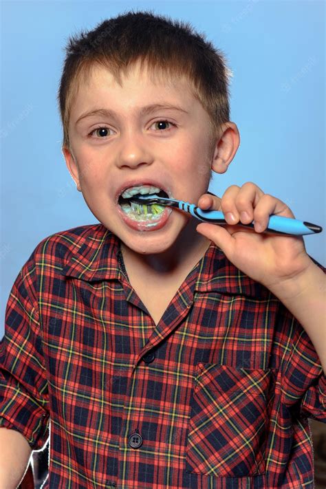 Premium Photo A Cute Boy In A Pajamas Brushes Teeth With Toothpaste
