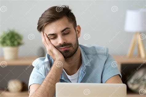 Bored Sleepy Man Feels Drowsy Resting On Hand Near Laptop Stock Image