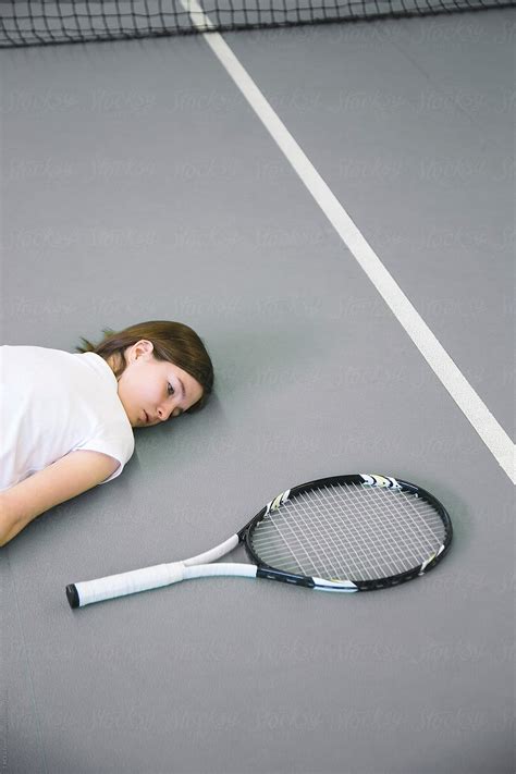 Girl Lying On Floor While Looking At Tennis Racket By Stocksy