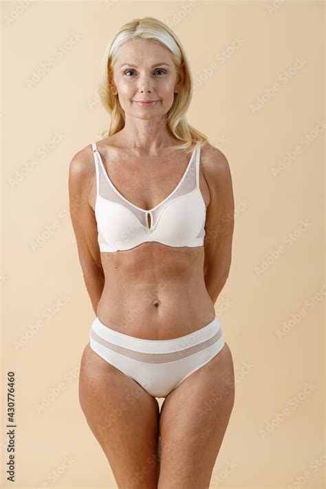 Studio Shot Of Beautiful Mature Woman With Blonde Hair In White Underwear Posing For Camera