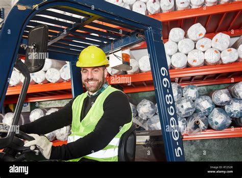 Warehouse worker as a forklift driver works on the forklift in the