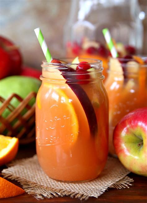 Two Mason Jars Filled With Orange Juice Apples And Orange Slices On A