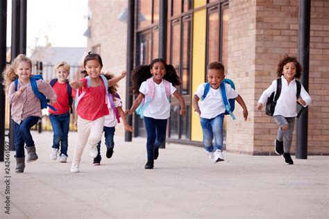 A Group Of Smiling Multi Ethnic School Kids Running In A Walkway