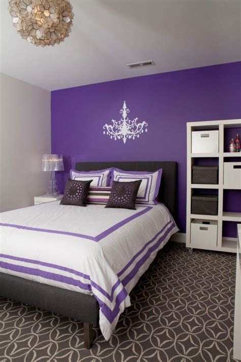 A colorful bedroom with deep purple panel walls, a blue bed and blue bedding, a hearth and a lamp on a branch. 20 Beautiful Purple Accent Wall Ideas