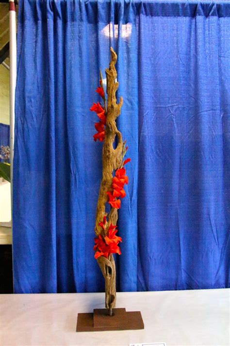 Flower arranging is the art of organizing the design elements of plant material and other components according to artistic principles to achieve beauty, harmony, distinction, and expression. 1st place: Barb Sheets. "Social Climber" a Vertical design ...