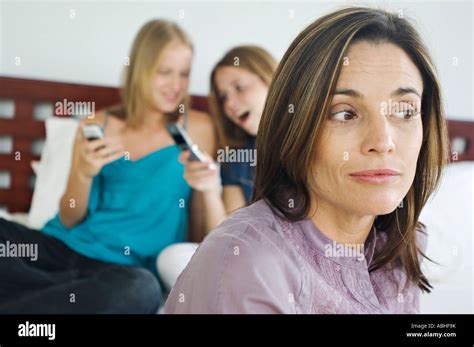 2 Teenage Girls Sitting On Bed Using Mobile Phones Thinking Woman In