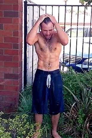 A Man Without A Shirt Standing In Front Of A Fence With His Hands On