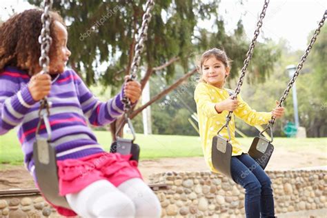Girls Playing On Swing In Playground — Stock Photo © Monkeybusiness