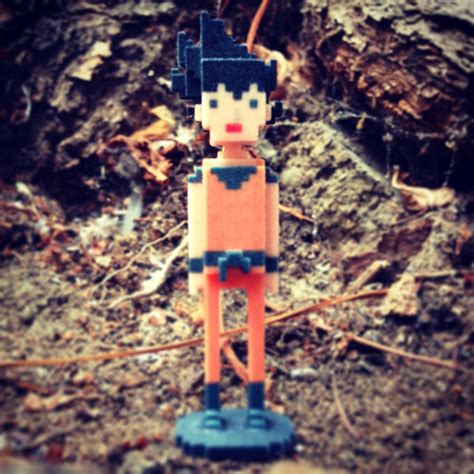 An Orange And Black Toy Standing On Top Of Dirt Covered Ground Next To