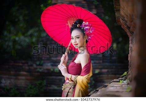 beautiful thai girl in traditional dress costume red umbrella as thai temple where is the public