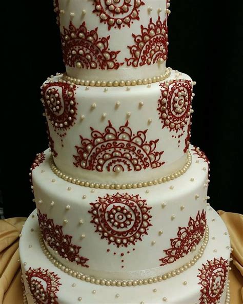 A Three Tiered Wedding Cake With Red And White Designs On The Side