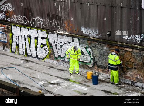 Two Men Removing Graffiti Paint From A Wall Stock Photo Alamy