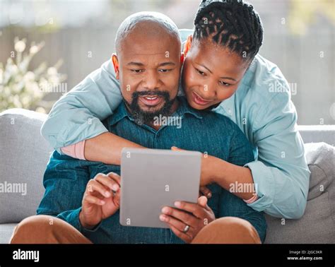 What Have You Been Up To A Mature Woman Hugging Her Husband While He Uses A Digital Tablet