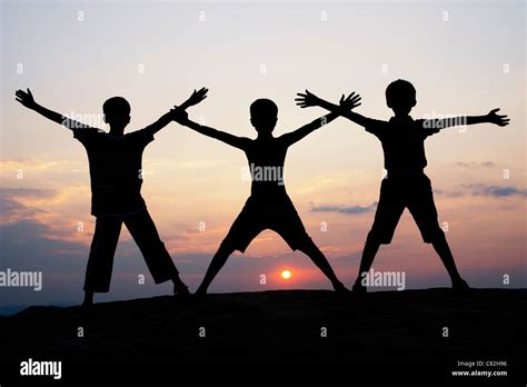 Silhouette Of Young Indian Boys Waving Against At Sunset India Stock