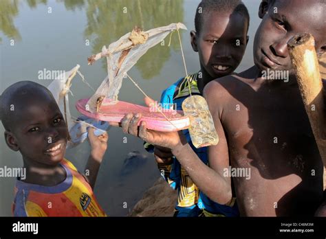 Three Songhai Children Show Off A Toy Boat Made From A Sandal And
